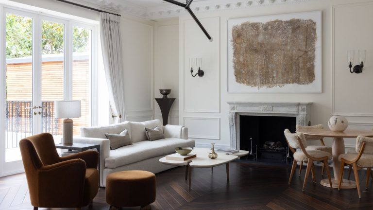 Neutral living room with wall paneling and large fireplace with print above