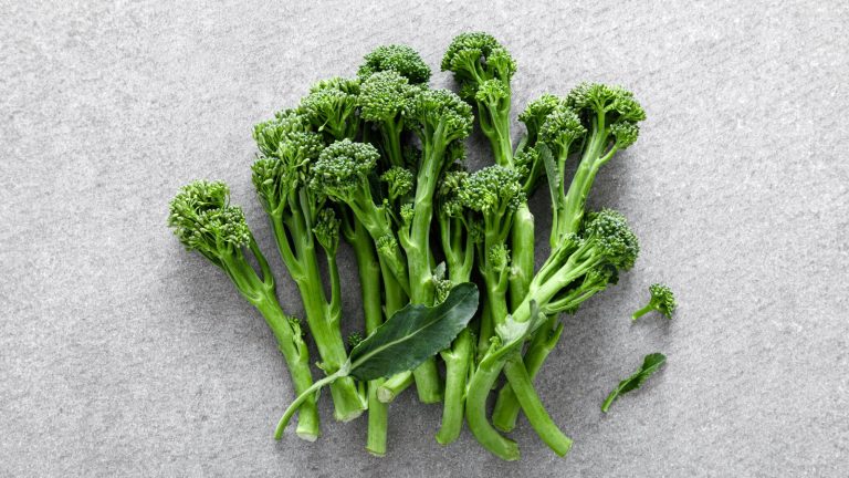 Cut broccolini stems and florets on a white surface