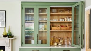 J’étais fatigué de devoir constamment coiffer mes armoires de cuisine à front en verre – ce hack Amazon de 7,99 $ a chié ma cuisine dans un instant en un instant pale green kitchen pantry cupboard with reeded glass cabinet doors filled with jars and wooden crates