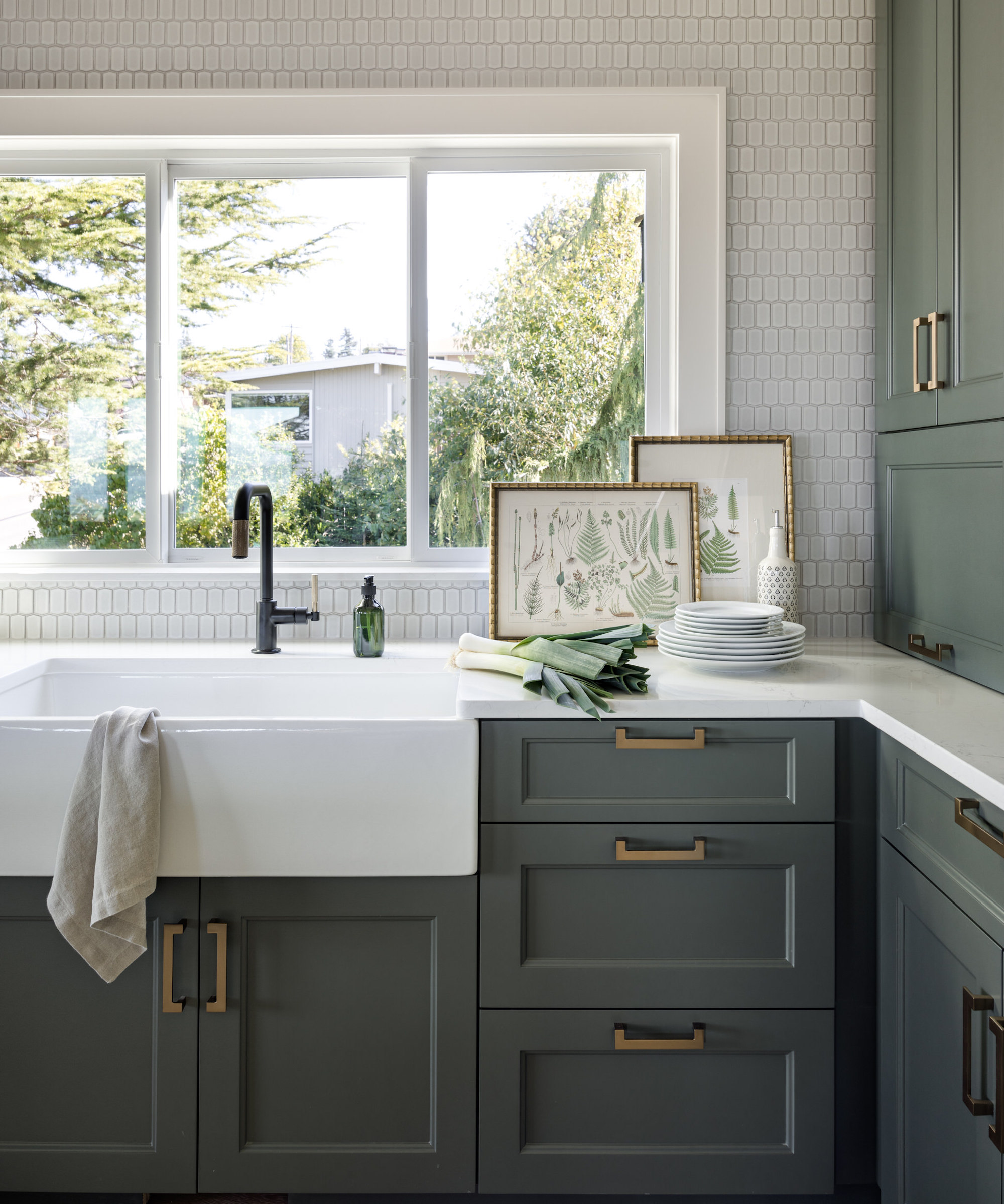 Détail de la cuisine avec armoires vertes, évier majordome et robinet noir