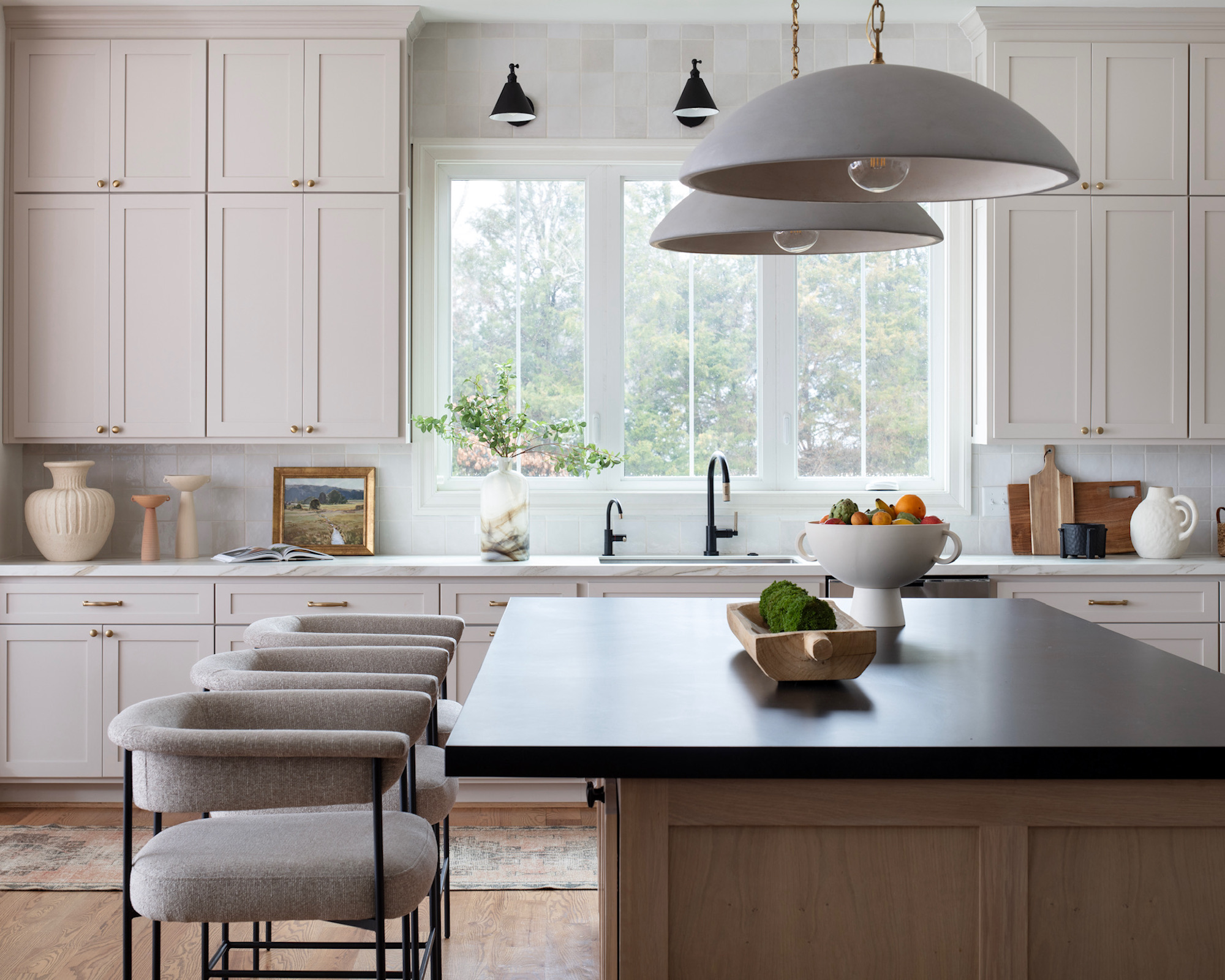 Cuisine avec armoires beiges, île en bois avec tabourets de bar rembourrés beiges et pendants et tabourets de bar noirs