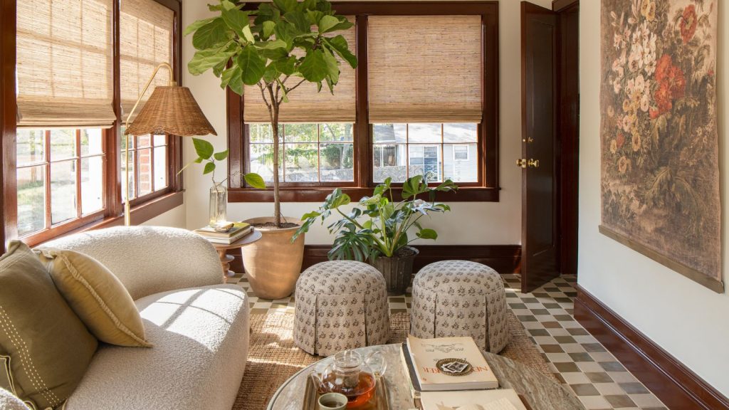 Sunroom with red window trim and floor trim, checkerboard floor, curved sofa, rattan lamp and floral ottomans