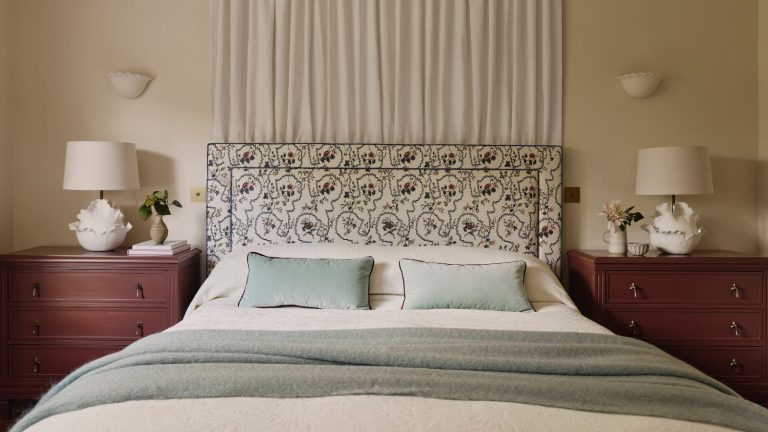Cette petite peinture inattendue Greene est étonnamment l’une des couleurs les plus polyvalentes que j’ai utilisées dans mon remodelage – voici pourquoi je pense que le brun chocolat peut fonctionner dans chaque pièce neutral modern meets traditional bedroom with a bed canopy, floral tapestry headboard and two large nightstands painted in a rich red chocolate brown color