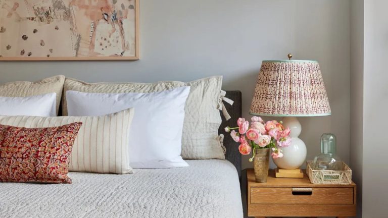 Ceci est un « neutral incontournable quand un espace a besoin de douceur » – pourquoi les concepteurs adorent utiliser l’étain le plus vendu de Benjamin Moore Griege bedroom with wooden bedside table, with fabric lamps and layered white and cream bedding