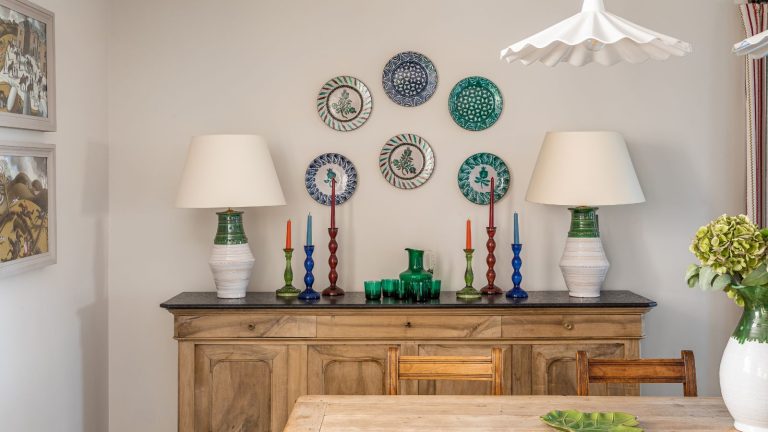 Dining room with wood console with candles, large lamps and plates on walls