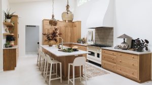 A large kitchen with white walls, marble countertops, and wooden cabinets