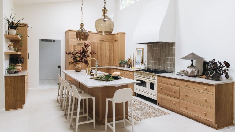 Si vous voulez concevoir une cuisine en 2025 qui va avoir l’air tout aussi élégant en 2045, prenez des notes de cet espace médimaliste A large kitchen with white walls, marble countertops, and wooden cabinets