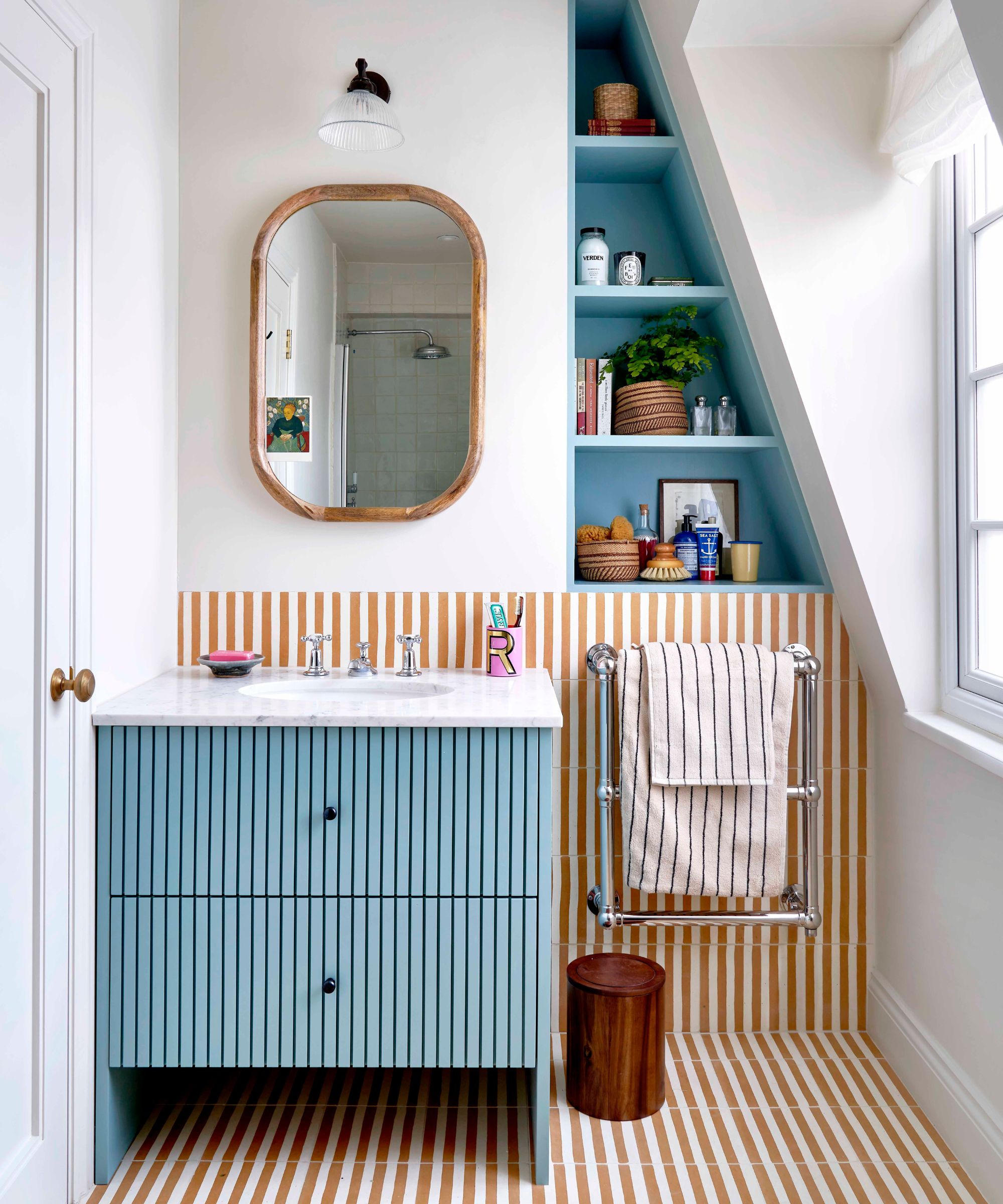 Petite salle de bain avec vanité bleue et tuiles rayées