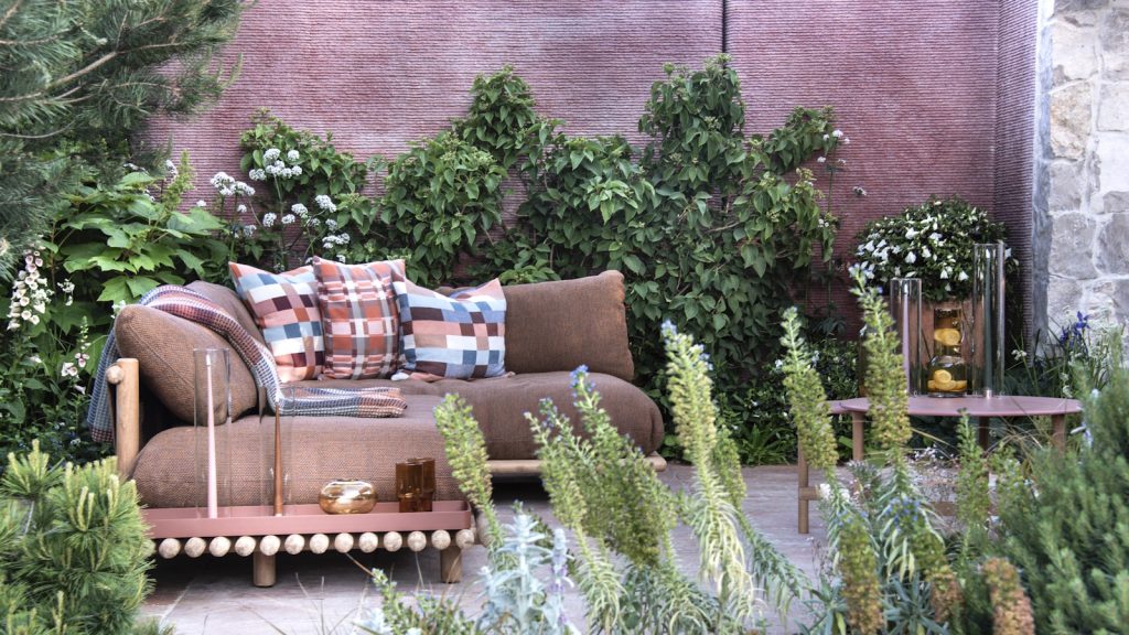 Small courtyard garden with bronze sofa and climbing plants