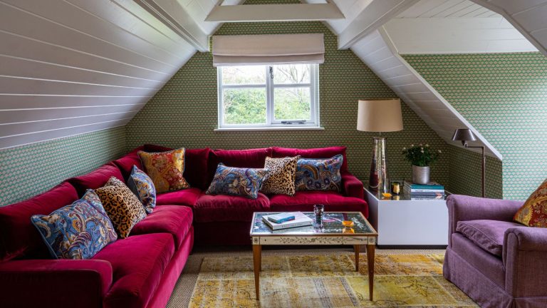 Êtes-vous coupable de «décoration dure»? C’est l’erreur de conception facile à faire wallpapered snug room set in a loft or attic space with a pitched panelled ceiling and green wallpaper with a large pink velvet couch