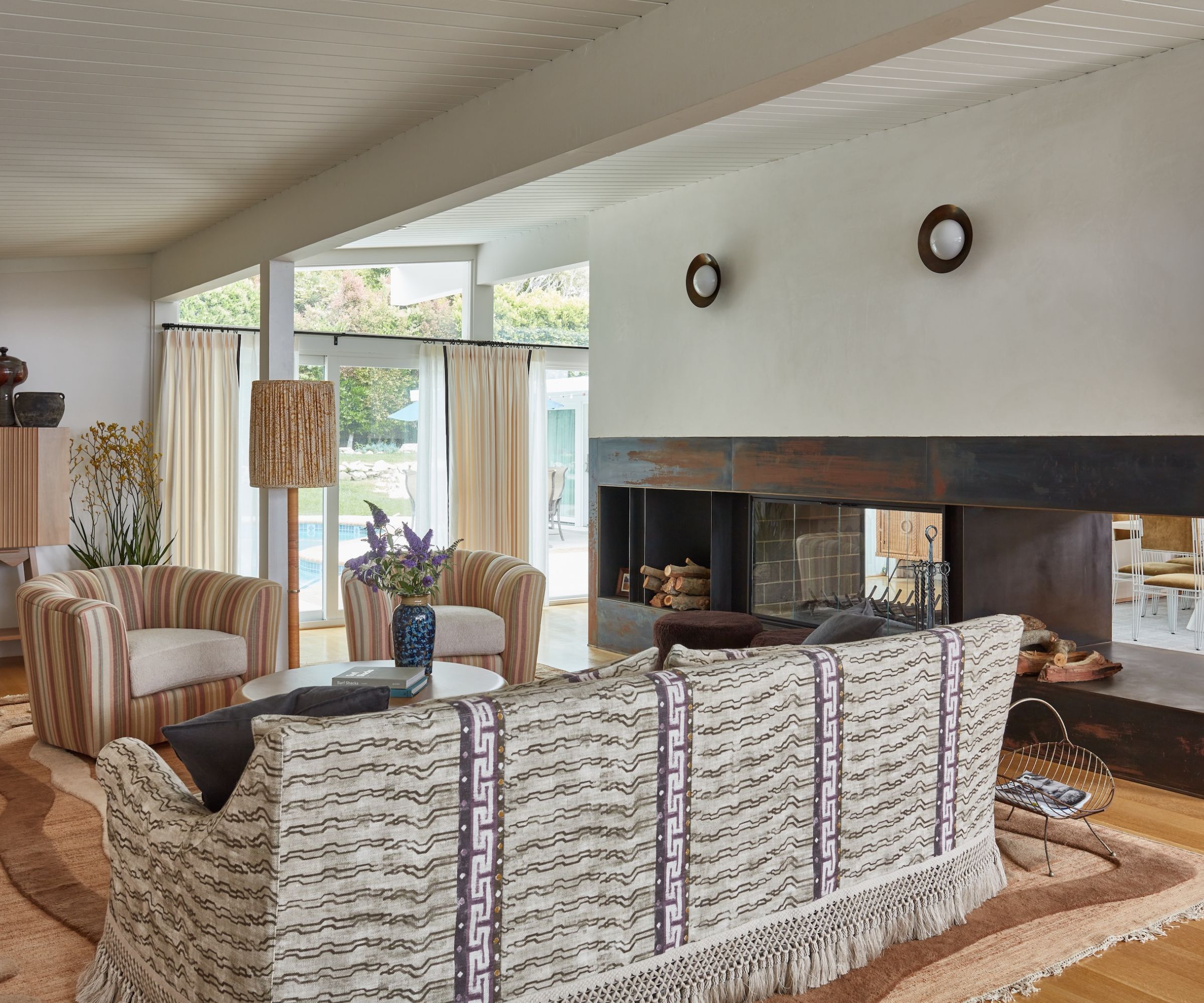 salon avec une palette de couleurs neutres terreux, des murs blancs et un canapé à motifs et des fauteuils