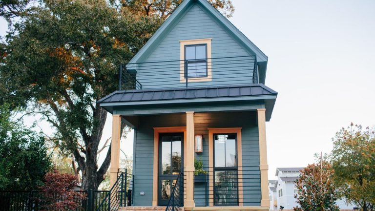 Qu’est-ce qu’une maison de fusil de chasse? L’histoire derrière ce petit style architectural unique en son genre Shotgun style house with painted blue exterior and wood pillars