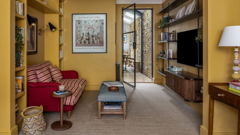yellow painted living room in farrow and ball's india yellow with custom shelves and a red and striped upholstered couch and small ottoman