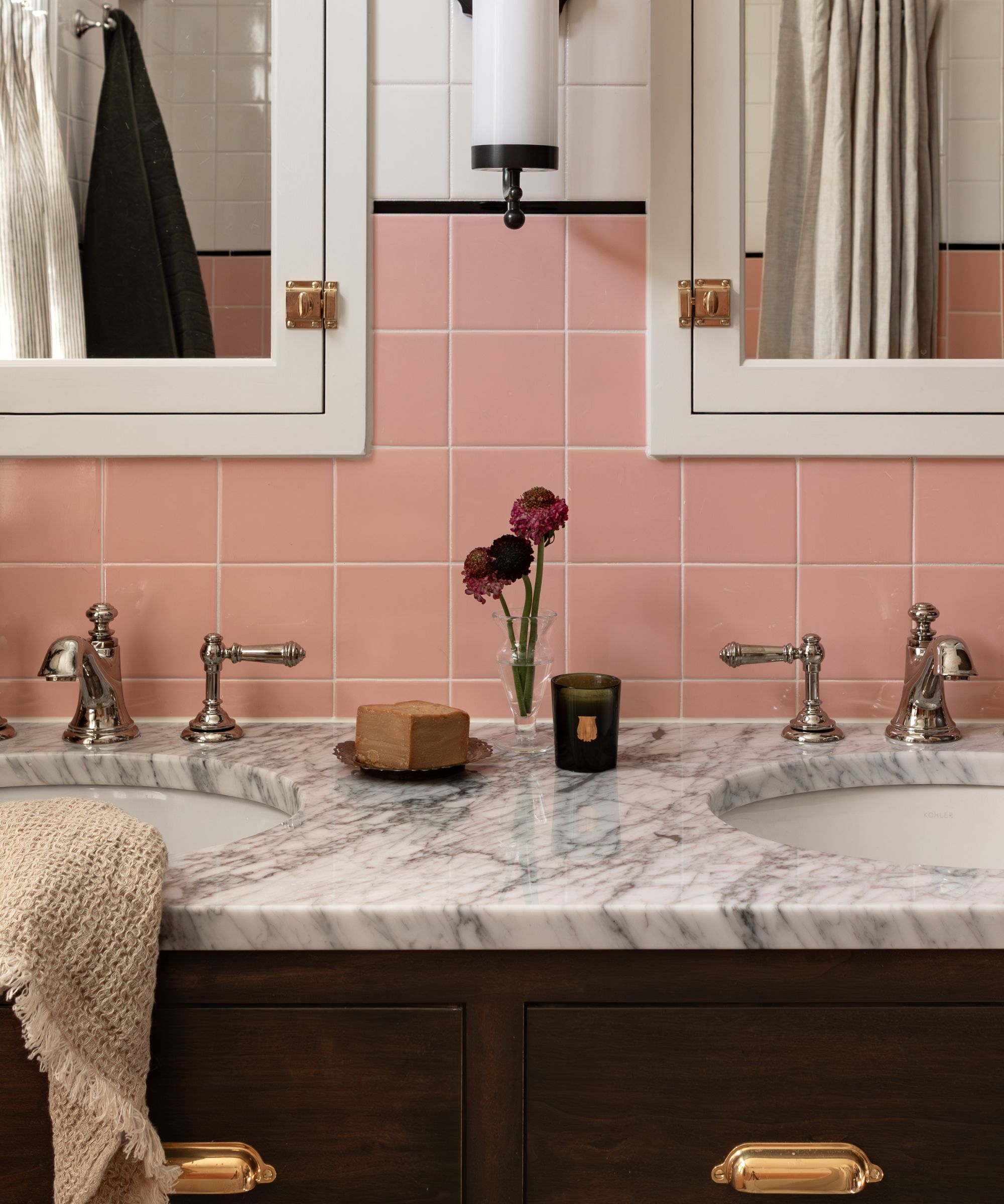 Salle de style de style vintage des années 40 avec carreaux muraux à moitié rose et blanc et armoires en bois foncé avec une vanité sur garniture en marbre double