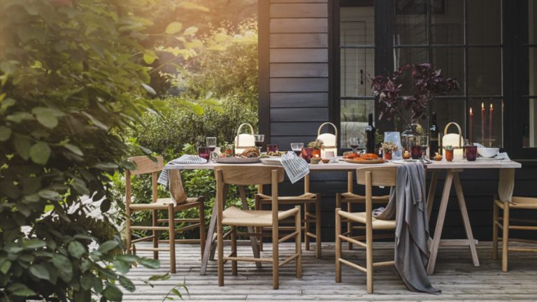 J’ai demandé aux concepteurs de partager les choses qui ont réellement transformé leur arrière-cour en 2025 – voici ce qu’ils ont dit A patio with table and chairs laid for a meal outdoors, candles lit, place settings and glasses and dishes of cooked food