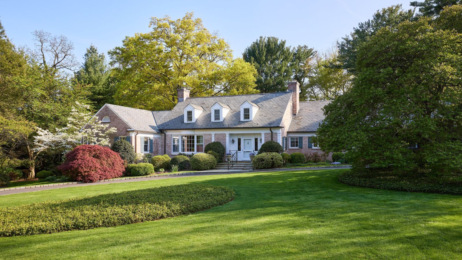 Maison de style fédéral avec façade en brique et pelouse pulpeuse