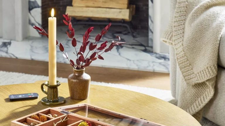 Ribbed Flameless Taper Candles from the Hearth &amp; Hand&trade; with Magnolia collection in a petite glazed ceramic candle holder next to a small neutral vase atop of a circular wooden coffee table