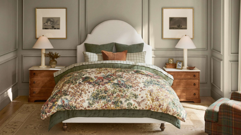 Florations, renards et faisans, oh mon Dieu! – La nouvelle collection d’automne de Pottery Barn est la gamme la plus merveilleusement fantaisiste que j’ai vue jusqu’à présent cette année a bedroom with a forest-themed bedspread, sage green painted walls, symmetrical bedside tables and lamps, and a plaid accent chair