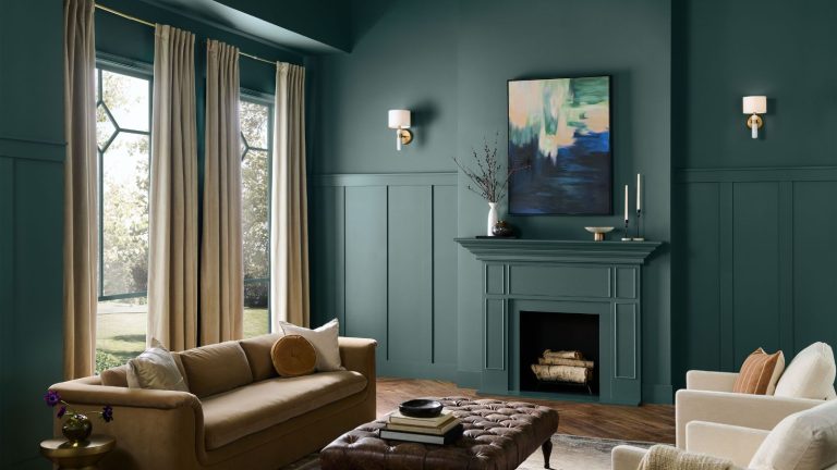 Le règne des peintures neutres est-elle finalement terminée? Behr lance la couleur de la saison de l’année avec un ton de jade fumé qui est aussi sophistiqué qu’audacieux Deep green painted living room with fireplace, large windows, beige sofa, leather ottoman and cream armchairs