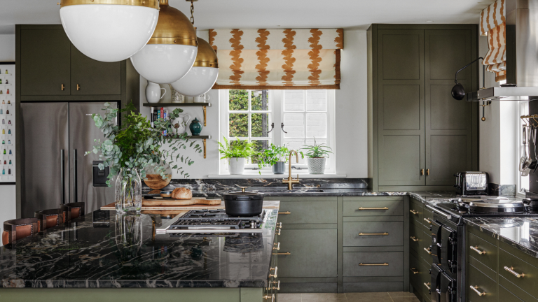 Une porte de réfrigérateur en désordre est-elle l’obstruction de votre cuisine? Ce piratage de bricolage intelligent apporte une commande sans effacer la personnalité – et il vous faudra moins de cinq minutes à faire a kitchen with green cabinets with gold hardware, black marble countertops, and gold pendant light fixtures