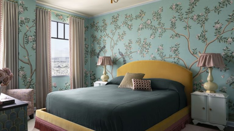 Vous ne devinez jamais que ce minuscule appartement de boîte à bijoux des années 1920 avait un lit murphy dans l’une de ses chambres les plus sophistiquées Bedroom with pale blue floral wallpaper, yellow velvet upholstered headboard and teal bedding