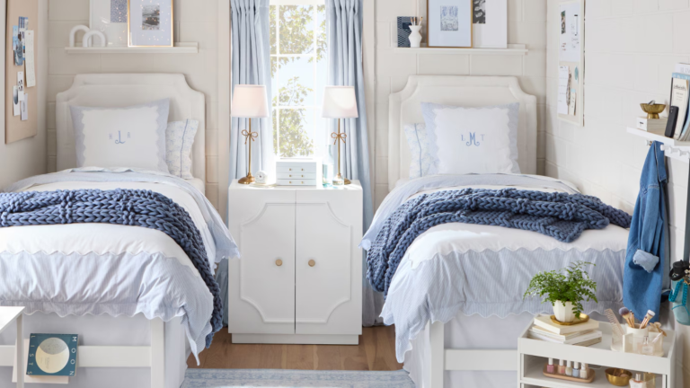 Coincé avec des murs de dortoir de parpaings? Ne paniquez pas, voici exactement comment les décorer pour créer un espace plus accueillant a dorm room with two matching twin beds with a blue color scheme and light tan walls