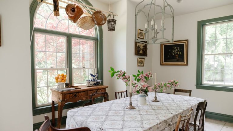 Toutes les cuisines rustiques les plus élégantes que je vois en ce moment ont cette fonctionnalité en commun – il est facile à reproduire et vous possédez probablement déjà tout ce dont vous avez besoin Vintage dining room with arched window, long dining table with white tablecloth, wood chairs and pendant light