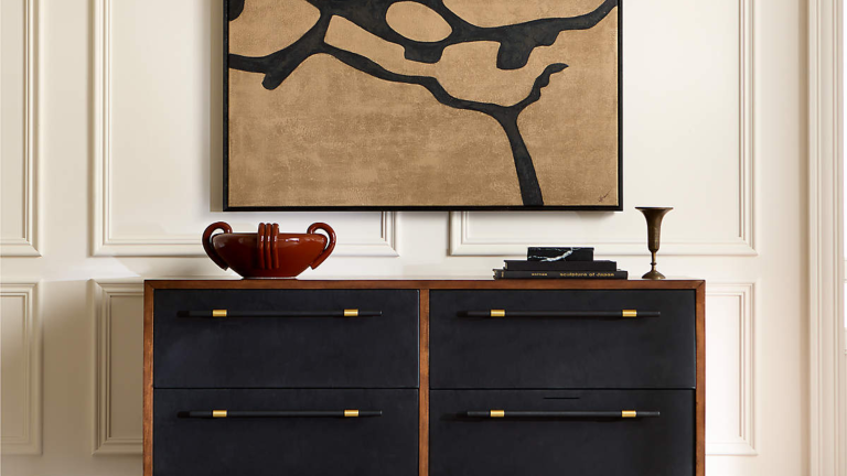 Je vous exhorte à abandonner vos plateaux à biberon pour quelque chose de bien plus utile – pourquoi je jure par un « bol à sac » pour guérir mon entrée chroniquement encombrée à la place Room with picture frame moulding, a black credenza holding a red lacquered ceramic bowl, and modern art hanging on the walls.
