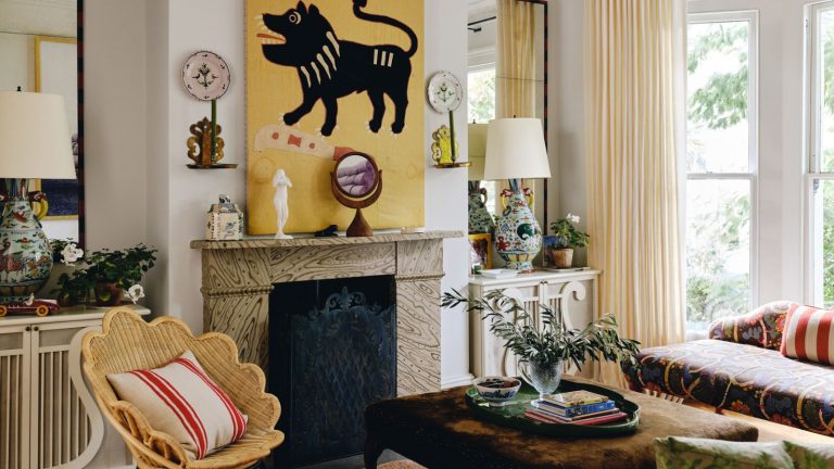 « Votre maison n’est pas assez bizarre, et c’est pourquoi il ressemble à ce que tout le monde soit » – ce conseil m’a fait sortir d’une ornière de design d’intérieur et maintenant je pense que tout le monde doit l’essayer aussi image of an eclectic living room with white walls and a large yellow painting above a marble fireplace with a scalloped rattan chair and eclectic furniture