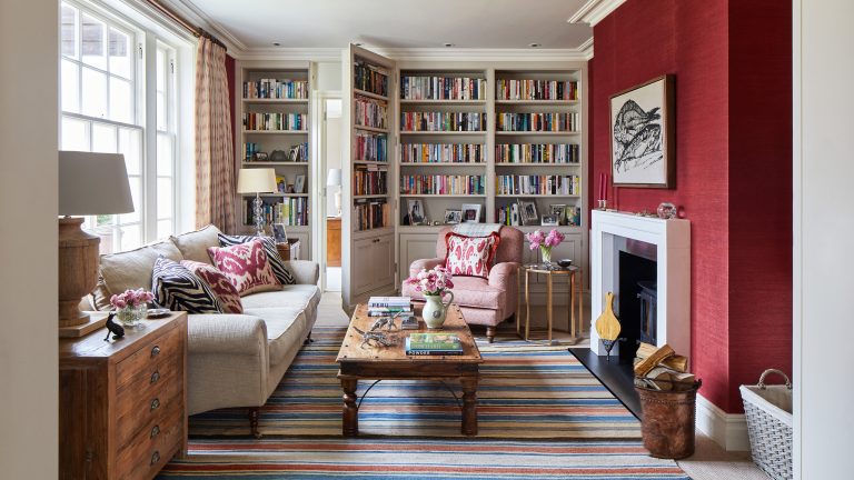 Ces 5 couleurs ont peut-être été populaires en 2025, mais les concepteurs disent qu’ils ne les utiliseraient jamais dans leur propre maison Crimson painted living room with large book case and sofa