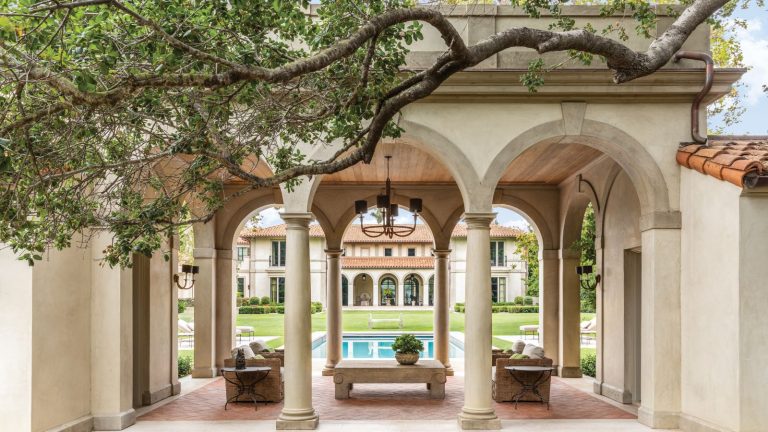 Qu’est-ce qu’une maison de style toscan? Tout ce que vous devez savoir sur cette conception architecturale inspirée de la Méditerranée Loggia courtyard with arched doorways and swimming pool and terracotta tiling with large curved tree