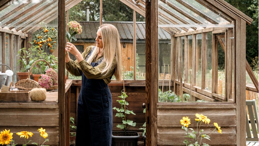 Woman in garden shed holding a cut hydrangea stem