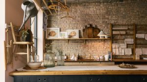 Ce sont les 5 meilleures couleurs à associer à un comptoir de cuisine en bois, selon des designers d’intérieur A Manhattan kitchen with an exposed stone wall, wooden countertops, and blue paneled cabinets