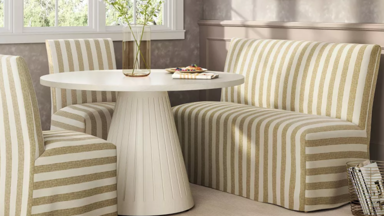 Vous cherchez de beaux sièges à banquette qui ne coûtent pas 1 000 $? Cette version cible à la vente fait fonctionner le look même dans la plus petite des cuisines Striped dining banquette and chairs clustered around a round dining table in a sunlit breakfast nook overlooking a window