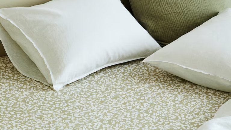 Je suis un minimaliste qui aime la literie blanche simple – mais cette nouvelle tendance pour ajouter un motif caché me fait craquer tranquillement mes manières neutres H&M Home botanical patterned fitted sheet in sage styled with white and coordinating sage pillows