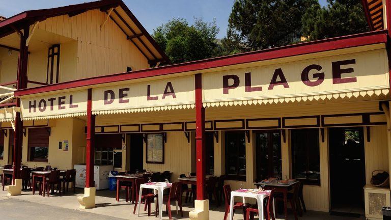 Je viens de voir le «Cape Cod of Europe» – voici comment les Français font le style de design d’intérieur côtier différemment hotel de la plage in cap ferret, france with yellow and red wooden building and tables set outside