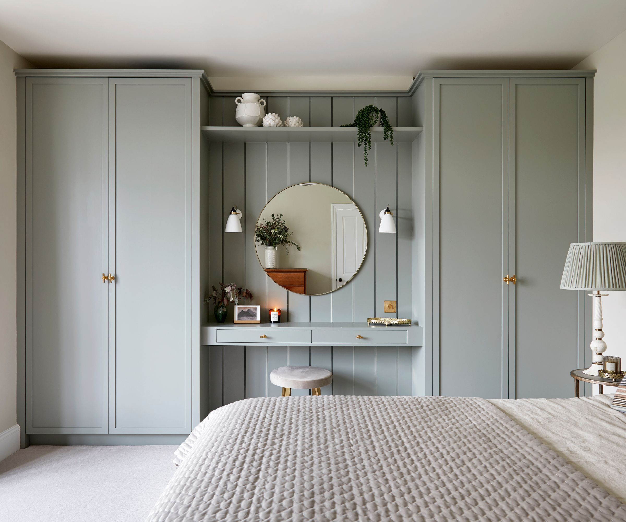 Chambre avec armoires intégrées et vanité peintes dans une peinture gris clair avec un tapis crème