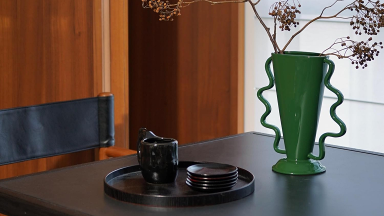 Ces 18 swaps Amazon sous le radar rendront votre maison à la maison pendant la nuit – et personne ne devinera d’où ils vont de Wavy daul-handled green vase sitting on a sleek black table in a warm, room-paneled dining room