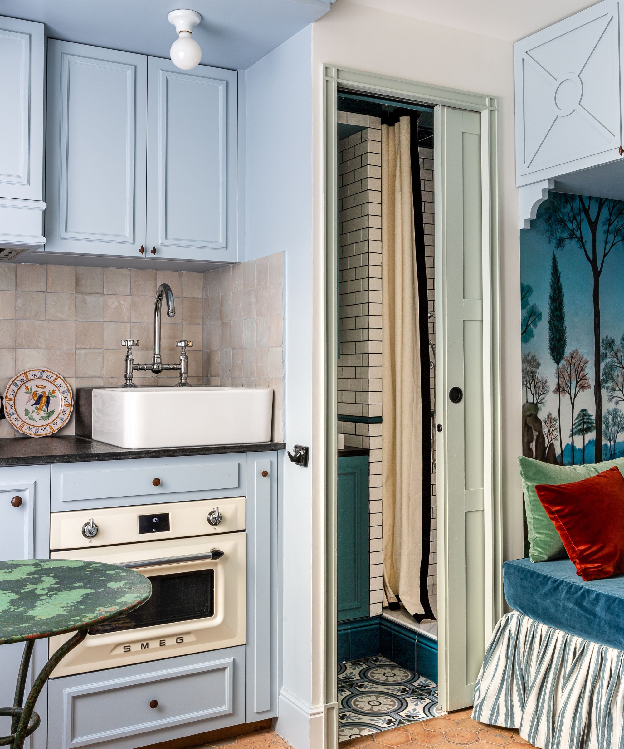 Cuisine bleue avec lit de repos dans un coin regardant dans la salle de bain avec des carreaux de métro