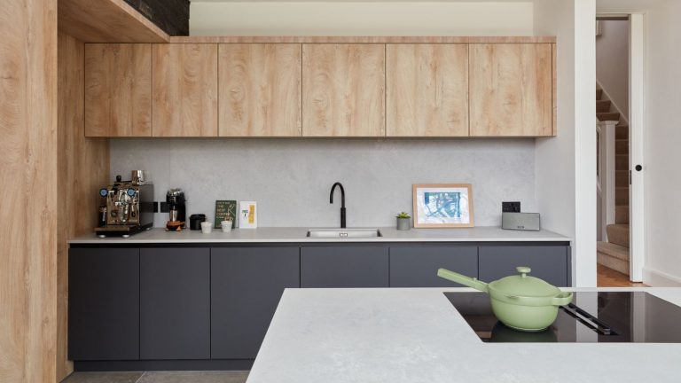 Les comptoirs de cuisine en béton sont tendances, mais sont-ils en fait une bonne idée? Les concepteurs préviennent qu’ils pourraient ne pas être le choix le plus pratique – voici pourquoi A modern kitchen with wood upper cabinets, dark blue lower cabinets, and concrete countertops