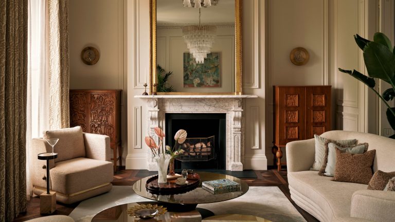 À l’intérieur d’une maison raffinée de Dublin où le patrimoine et la modernité coexistent sans effort Elegant living room with neutral walls, a stone marble fireplace with a gold mirror above and wooden cabinets in the alcoves