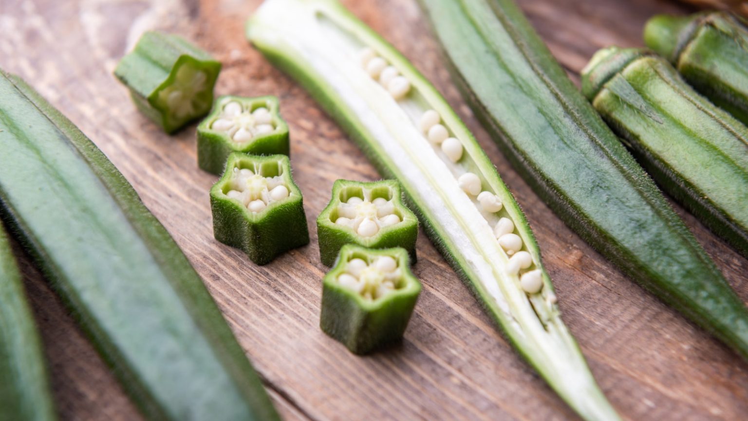 L’automne est le moment idéal pour récolter les graines de gombo – et la façon la plus simple de les récupérer pour semer l’année prochaine Fresh okra sliced open on a wooden table