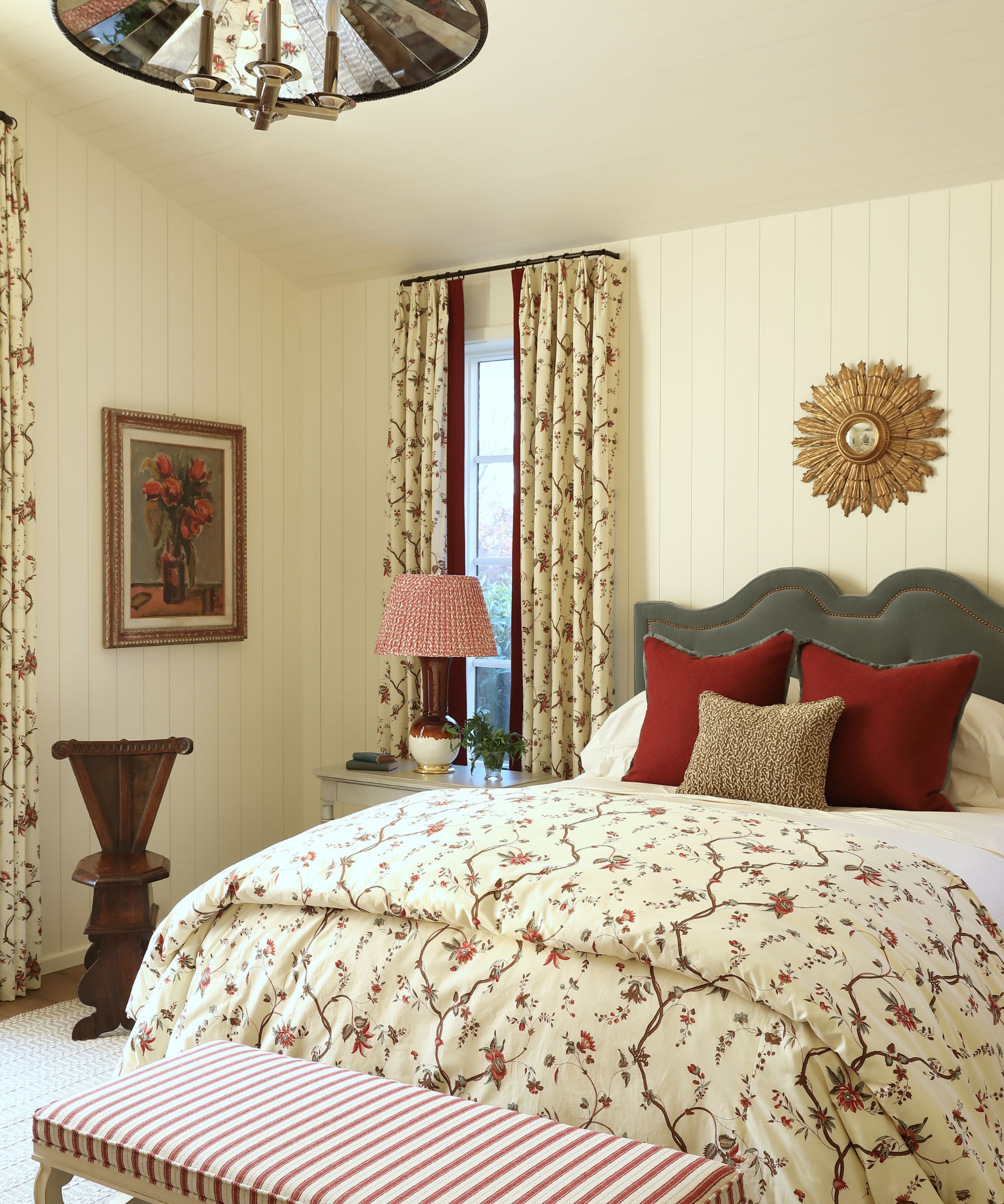 Chambre vintage avec murs à chapelet à la crème et plafond peint, rideaux floraux, lit double avec lancer floral et banc rayé