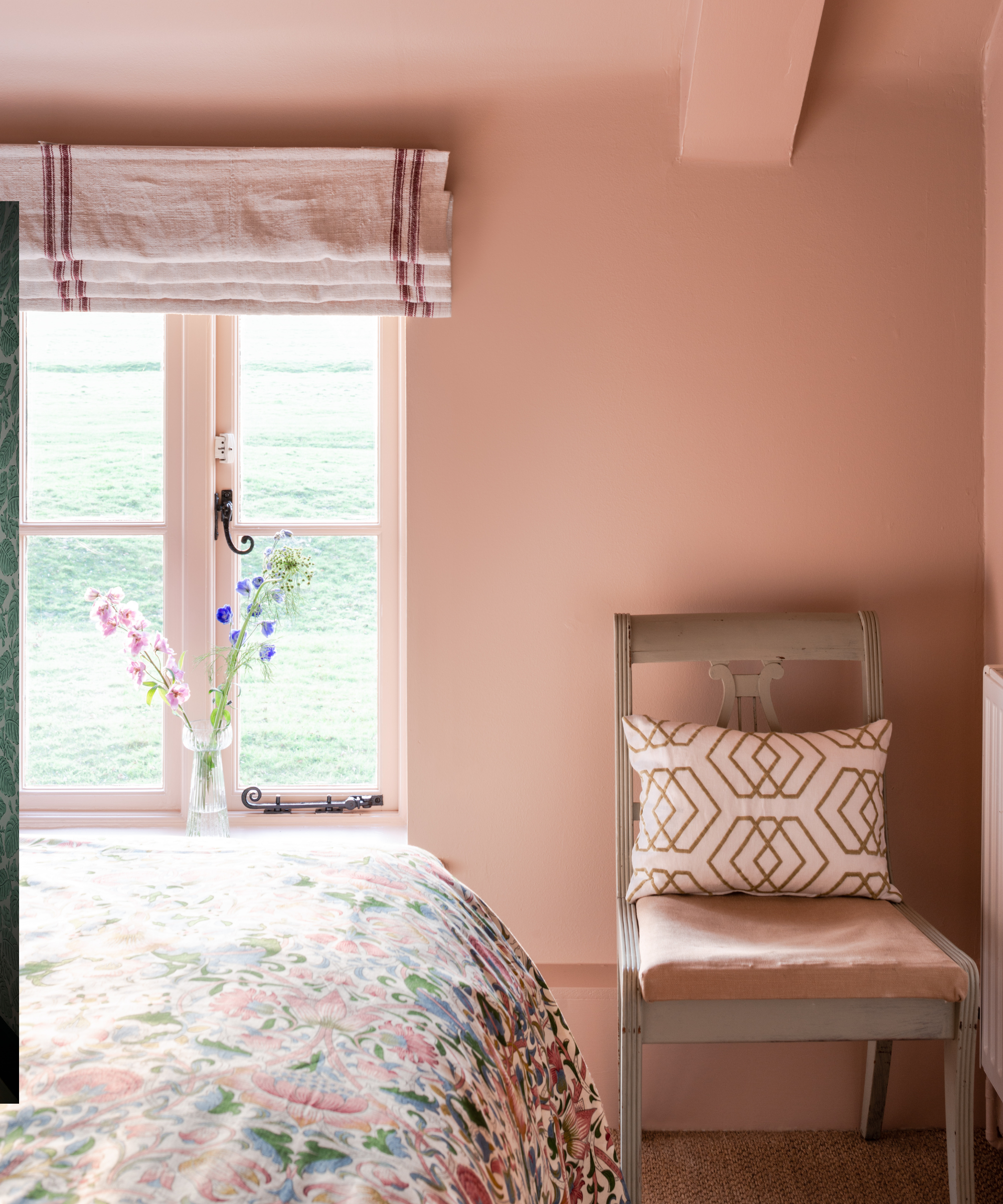 Chambre peinte en plâtre avec une chaise simple et une literie florale en vue