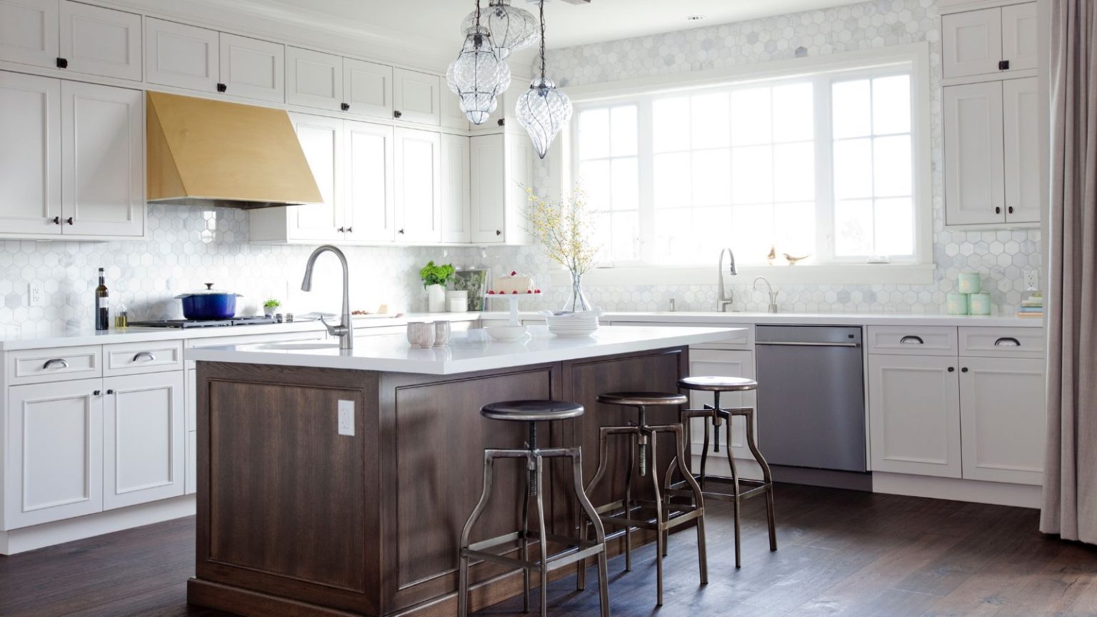 À quoi ressemblaient les cuisines les plus tendances il y a 10 ans ? Vous n’imaginez pas combien de choses ont changé en une décennie A 2015 kitchen with white cabinets, a wooden island, a brass range hood, and exposed appliances