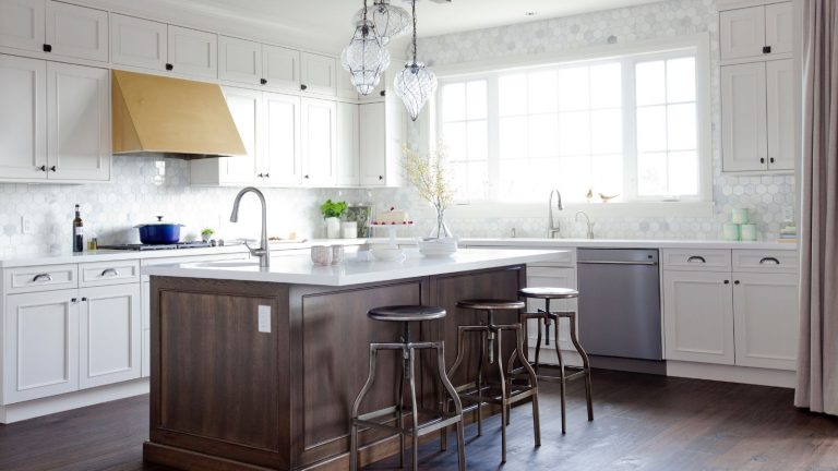 À quoi ressemblaient les cuisines les plus tendances il y a 10 ans ? Vous n’imaginez pas combien de choses ont changé en une décennie A 2015 kitchen with white cabinets, a wooden island, a brass range hood, and exposed appliances