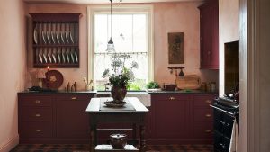 Cette couleur de luxe inattendue envahit tranquillement les cuisines du monde entier A small kitchen with textured walls, wine red cabinets, and a wooden freestanding island