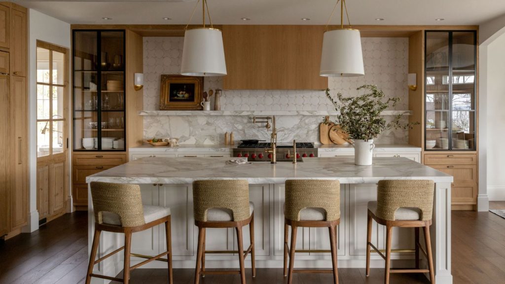 A warm neutral kitchen with wooden cabinets, a marble countersplash, and wall tiles to extend the backsplash