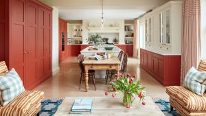 Alors vous souhaitez défaire votre cuisine à aire ouverte ? Voici comment rendre l’espace ouvert plus défini An open plan kitchen and living area with red cabinets and a blue rug beneath the seating area to create zones