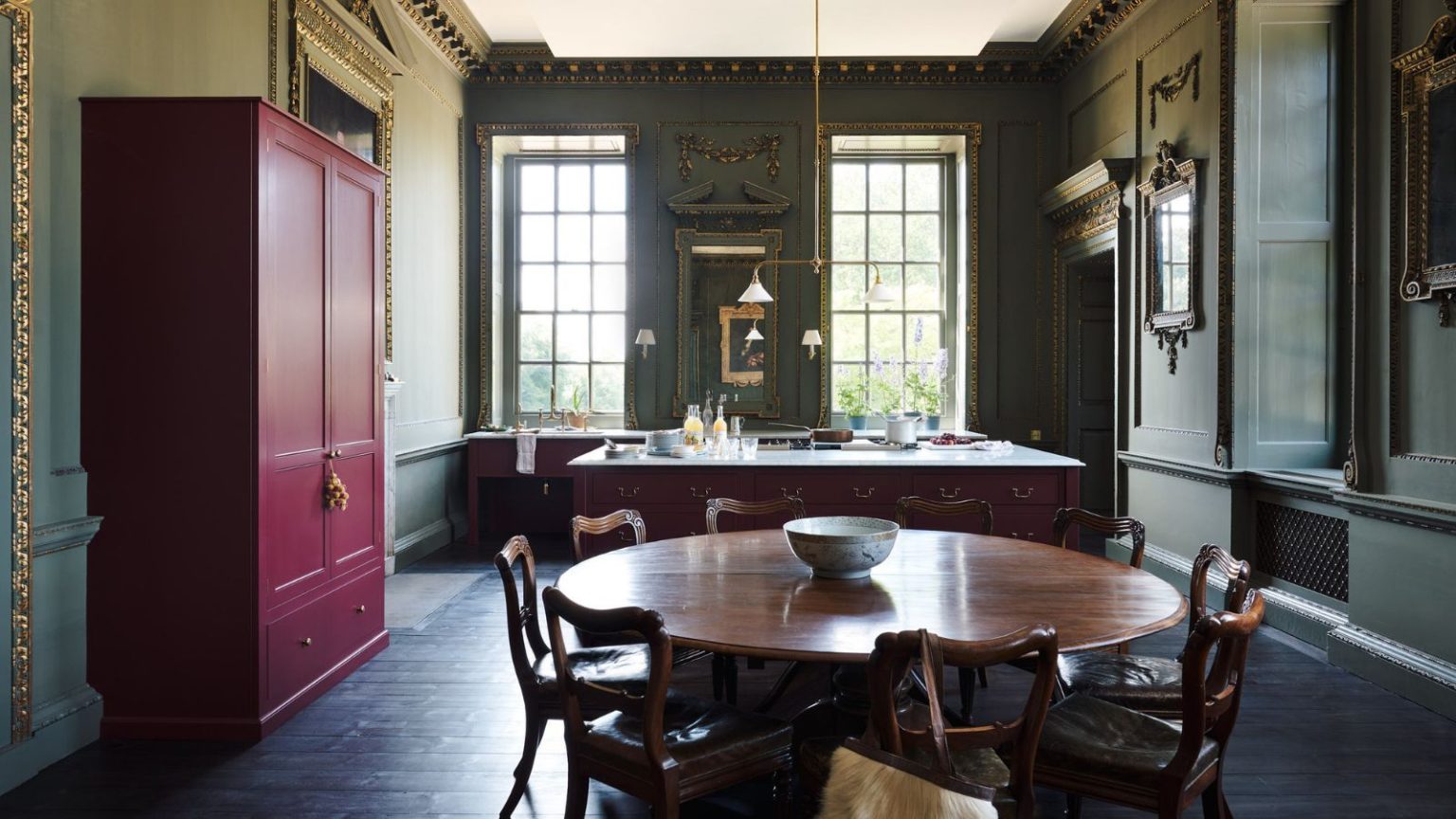 Cette cuisine élégante combine les deux plus grandes tendances de couleurs de 2026 – voici comment ces nuances audacieuses fonctionnent ensemble Raynham Hall kitchen with green walls, red cabinetry, and freestanding furniture